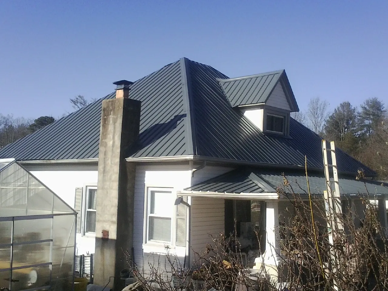 Dark blue standing seam metal roof on a white farmhouse with dormer — Slate & Tile Roof Repair by Roofing Brothers in Rye